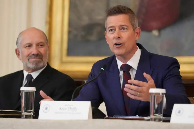Commerce Secretary Howard Lutnick listens as Transportation Secretary Sean Duffy speaks during a FIFA task force meeting on the 2026 FIFA World Cup with President Donald Trump in the East Room of the White House.