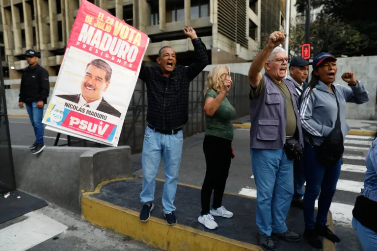Supporters display a poster of Venezuelan President Nicolás Maduro in Caracas, Venezuela, Saturday, Jan. 3, 2026, after U.S. President Donald Trump announced Maduro had been captured and flown out of the country. (AP Photo/Cristian Hernandez)