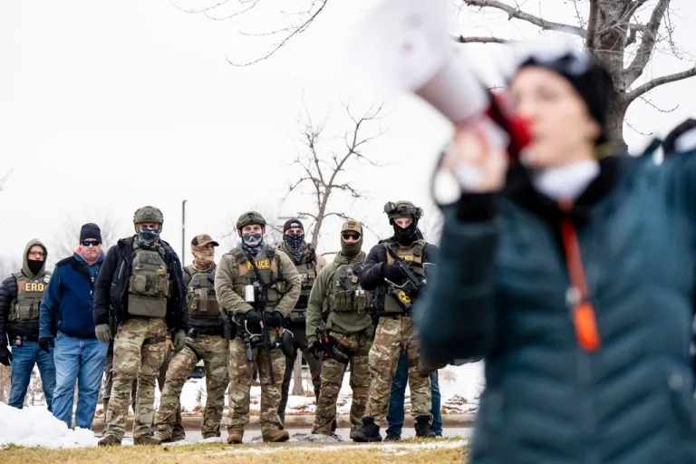 Protesters gather outside the Bishop Henry Whipple Federal Building guarded by police and federal agents, in Minneapolis.