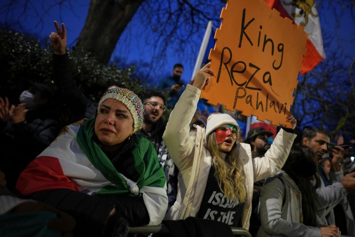 Protesters hold up placards and flags as they demonstrate outside the Iranian Embassy in London, Monday, Jan. 12, 2026. 