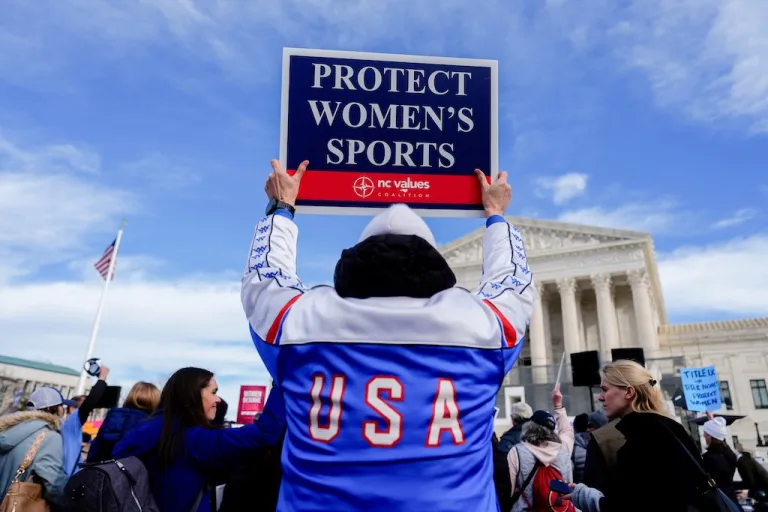 A protester holds a sign outside the Supreme Court during arguments over state laws limiting women's sports to biological women on Jan. 13, 2026, in Washington. (AP Photo/Julia Demaree Nikhinson)