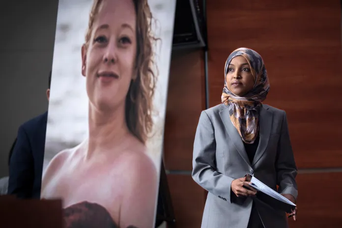 Rep. Ilhan Omar, D-Minn., walks beside a photograph of Renee Good, the woman shot and killed in her car by a federal immigration agent in Minneapolis, during a news conference with the Congressional Progressive Caucus as they announce an effort to limit funding for the Department of Homeland Security, at the Capitol in Washington, Tuesday, Jan. 13, 2026. (AP Photo/J. Scott Applewhite)