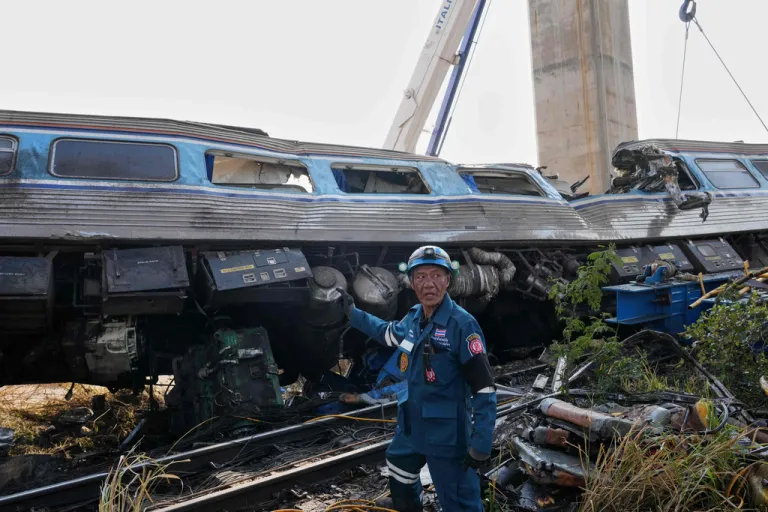 A rescuer stands near the wreckage after a construction crane fell into a passenger train in Nakhon Ratchasima province, Thailand, Wednesday, Jan.14, 2026.