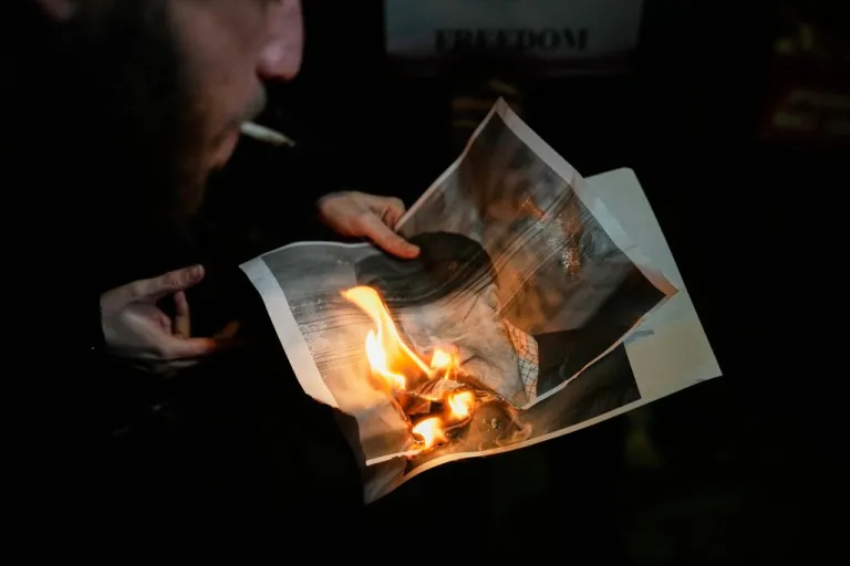 Demonstrators burn a poster depicting Iran's Supreme Leader Ayatollah Ali Khamenei during a rally in support of anti-government protests in Iran.