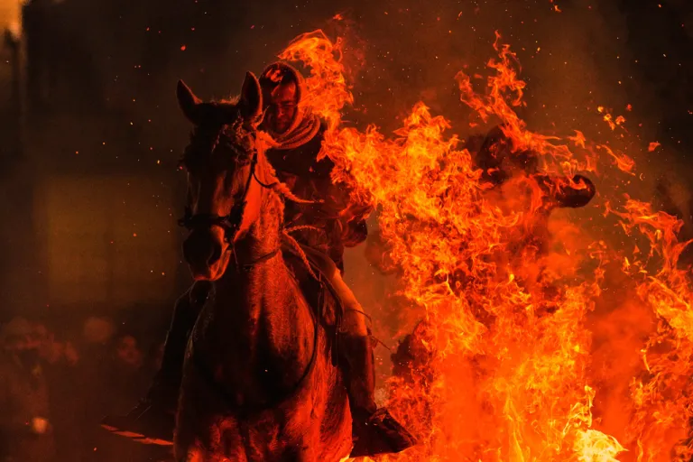 A man rides a horse through a bonfire as part of a ritual in honor of Saint Anthony the Abbot, the patron saint of domestic animals, in San Bartolome de Pinares, Spain, Friday, Jan. 16, 2026.