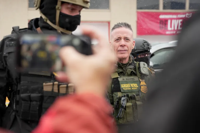 U.S. Border Patrol Cmdr. Gregory Bovino walks with Federal agents outside a convenience store on Wednesday in Minneapolis
