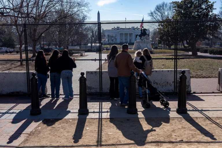 People look through the fencing placed around Lafayette Park near the White House while renovations are underway, Jan. 22, 2026, in Washington.
