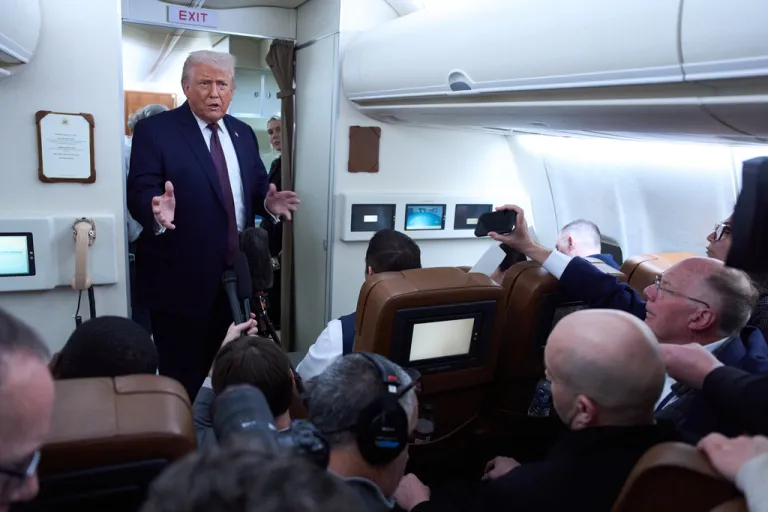 President Donald Trump speaks with reporters aboard Air Force One.