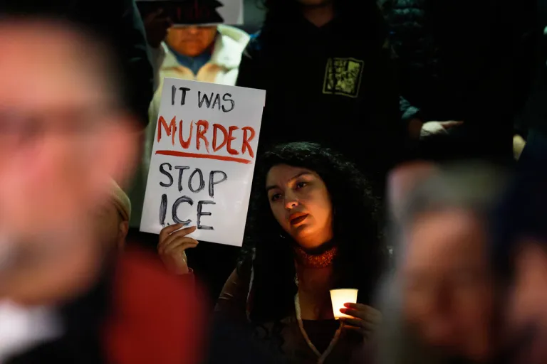A demonstrator holds a sign during a candlelight vigil during a protest in response to the fatal shooting of 37-year-old Alex Pretti in Minneapolis earlier in the day.