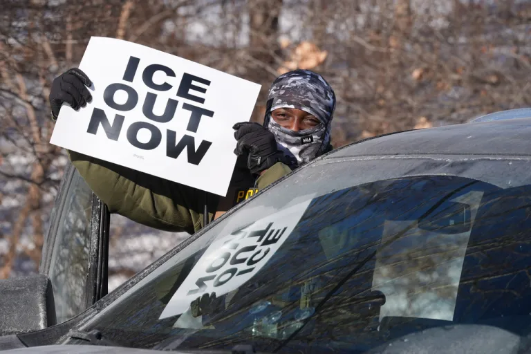Anti-ICE protestor waves sign saying 