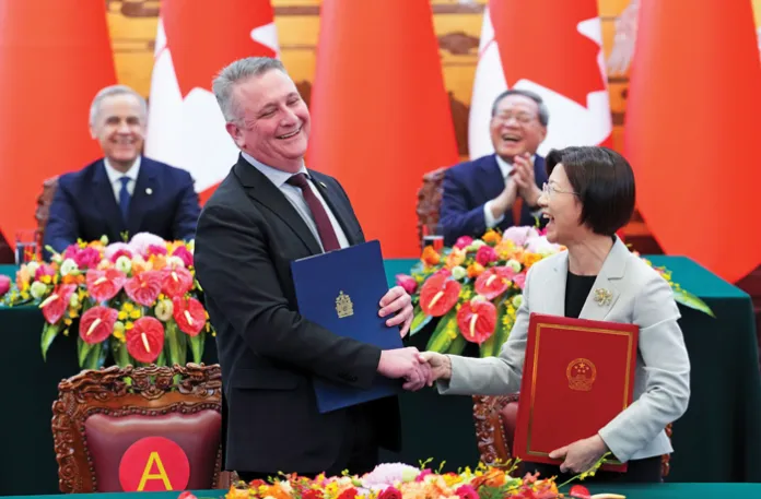 Canadian Prime Minister Mark Carney, back left, and Premier of China Li Qiang, back right, look on as Canadian Minister of Agriculture and Agri-Food Heath MacDonald, front left, and Sun Meijun, minister of the General Administration of Customs in China take part in a signing ceremony in Beijing, Jan. 15, 2026. (Sean Kilpatrick/The Canadian Press/AP)