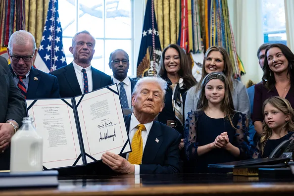 US President Donald Trump displays a signed bill during a ceremony in the Oval Office of the White House in Washington, DC, US, on Wednesday, Jan. 14, 2026. President Donald Trump will sign legislation Wednesday allowing schools that participate in a federal lunch program to serve whole milk, the latest measure advancing his administration's health agenda.