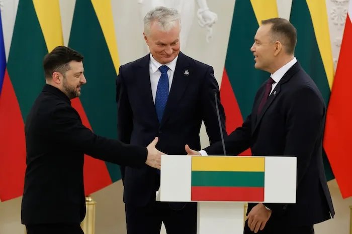 Ukrainian President Volodymyr Zelensky, left, and Polish President Karol Nawrocki, right, shake hands as Lithuania's President Gitanas Nauseda looks at them after a joint press conference at the Presidential palace in Vilnius, Lithuania, Sunday, Jan. 25, 2026.