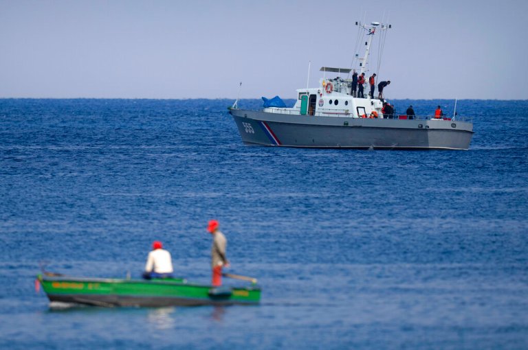 Fishermen watch a Cuban Coast Guards boat capture people traveling in a makeshift boat