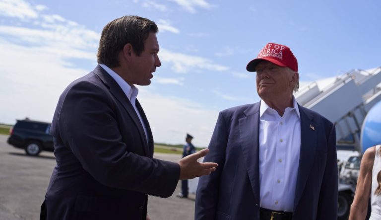 President Donald Trump listens as Gov. Ron DeSantis, R-Fla., speaks with reporters after arriving at Dade-Collier Training and Transition Airport, Tuesday, July 1, 2025, in Ochopee, Fla. (AP Photo/Evan Vucci)