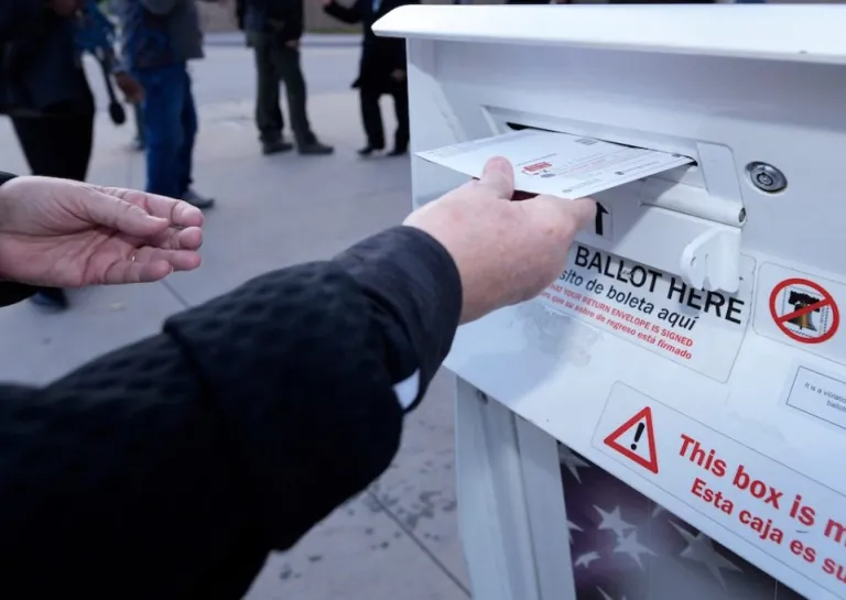 A voter places a ballot in a drop box.