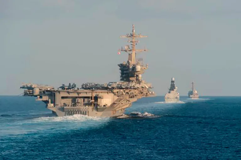 The aircraft carrier USS Abraham Lincoln, the air-defense destroyer HMS Defender, and the guided-missile destroyer USS Farragut transit the Strait of Hormuz.