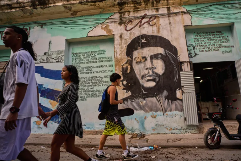 People walk past a mural of Che Guevara in Havana
