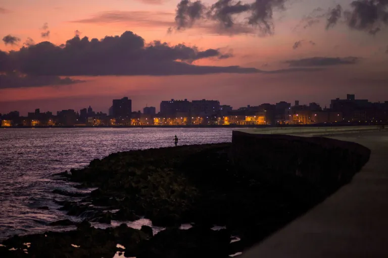 A fisherman casts his line along the Malecon at sunrise.