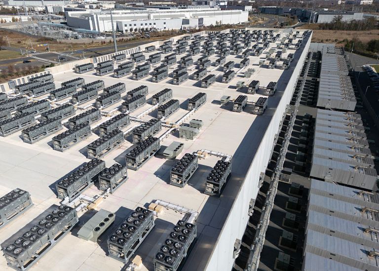 An aerial view shows cooling vent fans on the roof next to generators on the lower level of a Digital Realty data center in Ashburn, Virginia on November 12, 2025. Data centers are the physical infrastructure that make our digital lives possible, yet most people have never seen one up close or understand how they operate. Roughly 12,000 data centers are in operation in the world, with about half in the US, according to Cloudscene, a data center directory. (Photo by ANDREW CABALLERO-REYNOLDS / AFP via Getty Images)