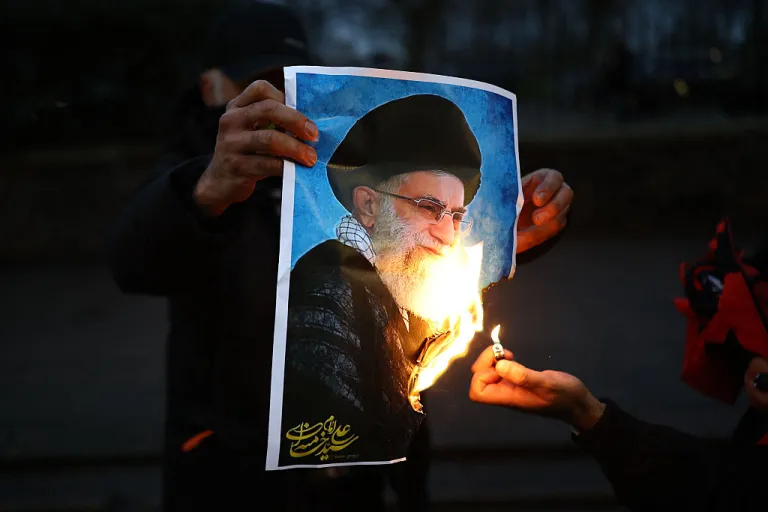 Anti-Iranian regime protesters burn an image of Ayatollah Ali Khamenei, during a gathering outside the Iranian Embassy, central London, on January 12, 2026. (Photo by Henry NICHOLLS / AFP via Getty Images)