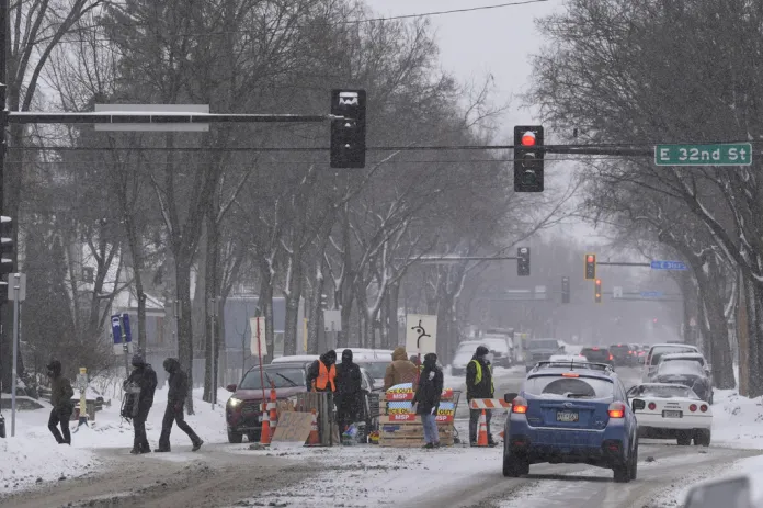 People stand near a blockade set up to deter federal immigration enforcement vehicles In Minneapolis, Sunday, Feb. 1, 2026. (AP Photo/Alex Brandon)