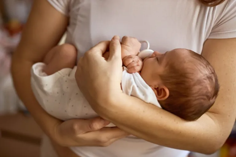 A woman holds a newborn baby in her arms. (Getty Images)