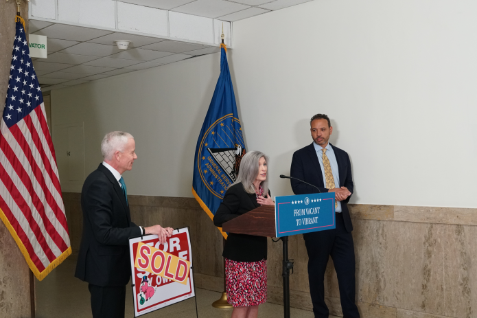 Sen. Ernst, Eric Mulata of Dalian Development, and GSA
Administrator Edward C. Forst stand with "sold" sign. 
