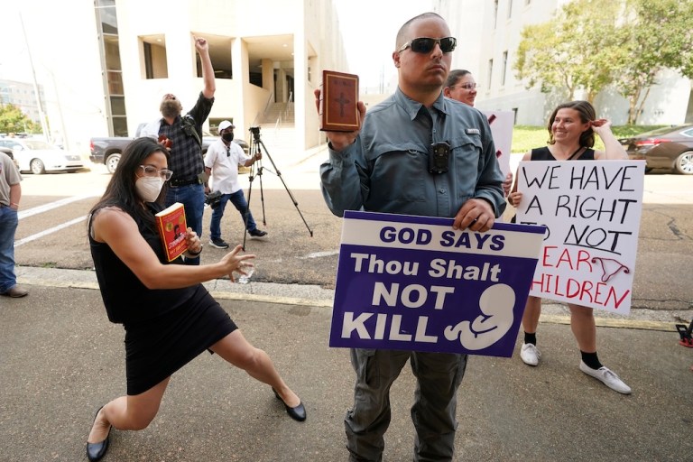 Anti-abortion activist Gabriel Olivier, center, holds his Bible and a message sign outside the Hinds County Chancery Court, Tuesday, July 5, 2022, in Jackson, Miss. (AP Photo/Rogelio V. Solis)