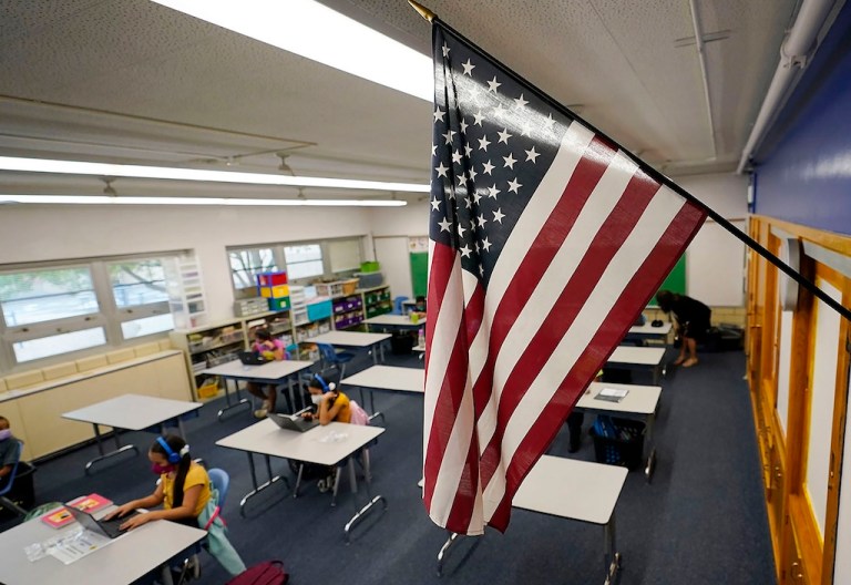 FILE - An American flag hangs in a classroom as students work on laptops, Aug. 25, 2020, in Denver. (AP Photo/David Zalubowski, File)