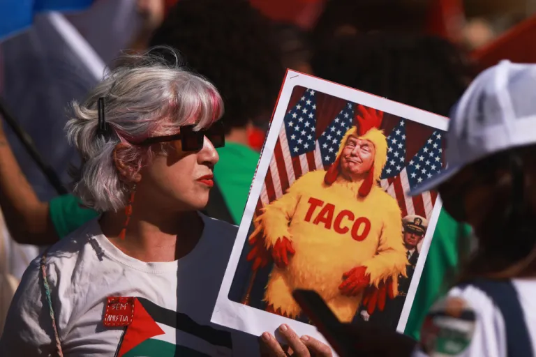 A demonstrator holds an illustration of U.S. President Donald Trump wearing a chicken costume during a protest against the 50% U.S. tariff on Brazilian goods outside the U.S. consulate in Brasilia, Friday, Aug. 1, 2025. (AP Photo/Luis Nova)