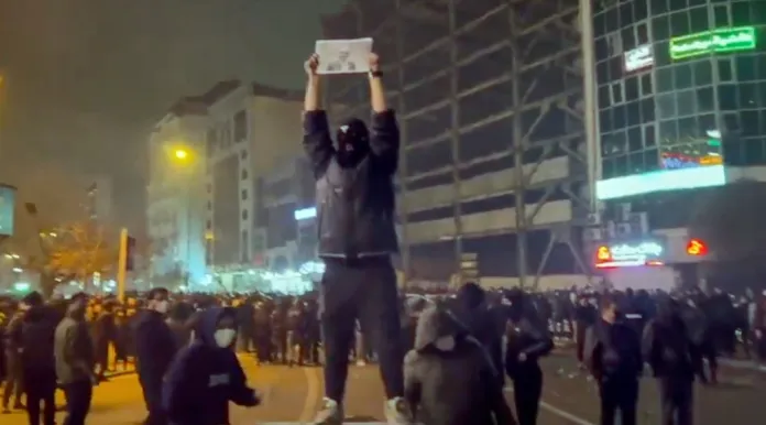 A protestor in Iran holds up a photo of Reza Pahlavi