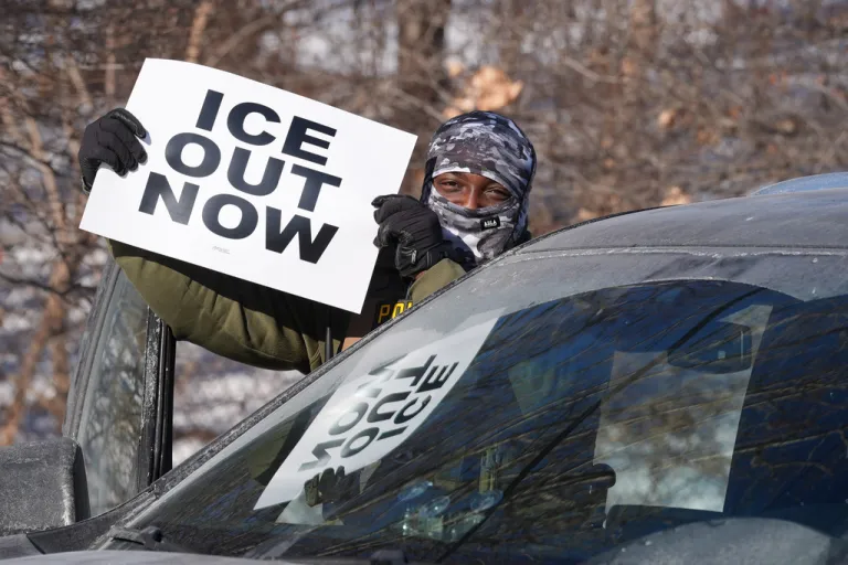 A protester holds a sign demanding federal immigration officers to leave the area.