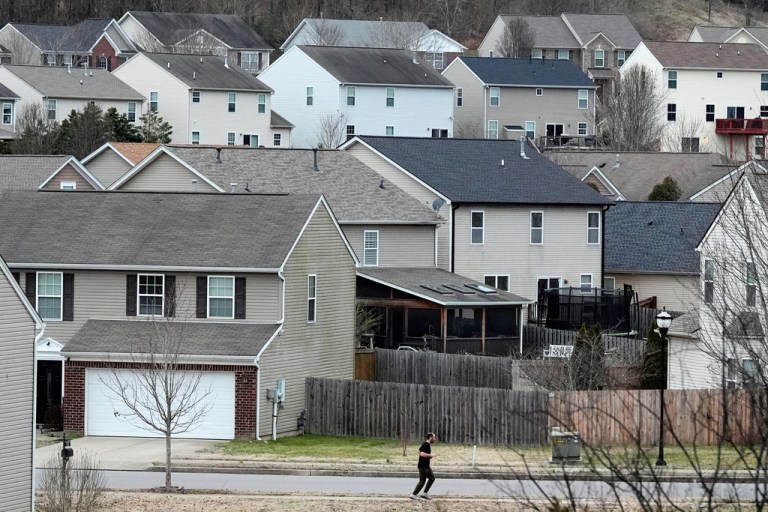 A person jogs past single family homes.