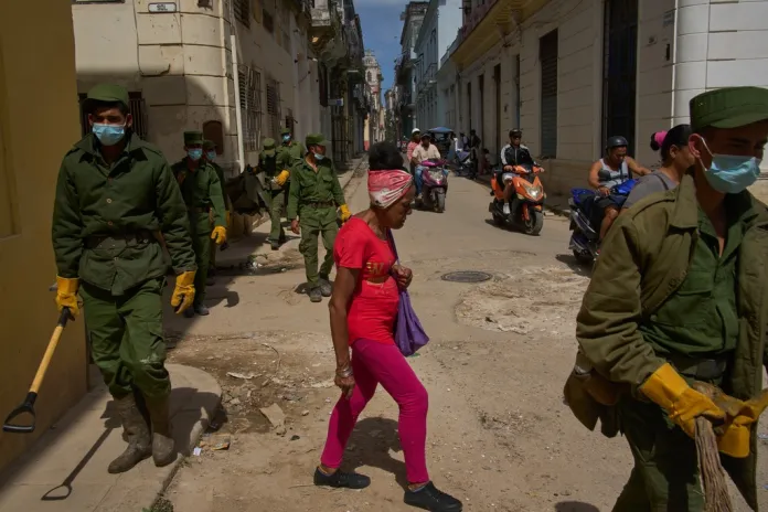 Cuban soldiers walk the streets of Havana picking up trash