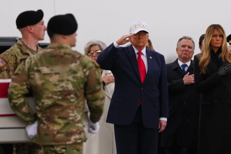 President Donald Trump salutes as an Army carry team moves the flag-draped transfer case containing the remains of six U.S. service members.