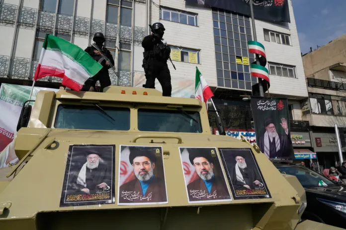 Policemen stand atop their car, with pictures of the late Iranian Ayatollah Ali Khamenei and his successor and son, Ayatollah Mojtaba Khamenei.