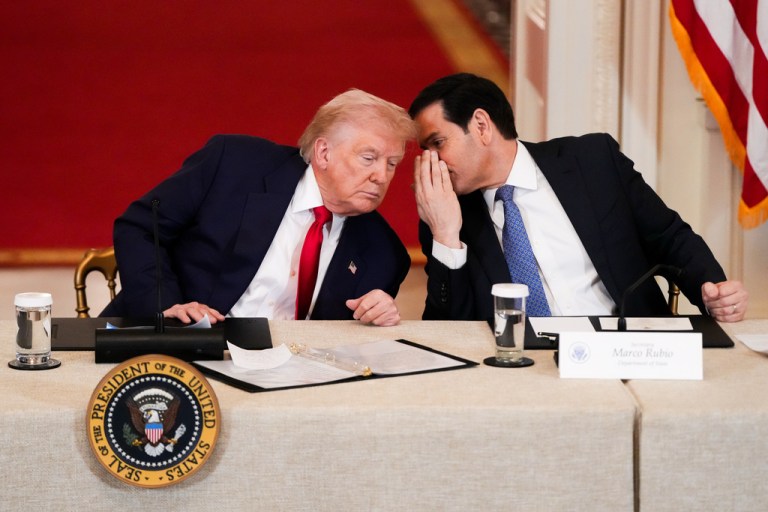 President Donald Trump speaks with Secretary of State Marco Rubio during a roundtable discussion on college sports in the East Room of the White House, Friday, March 6, 2026, in Washington. (AP Photo/Julia Demaree Nikhinson)