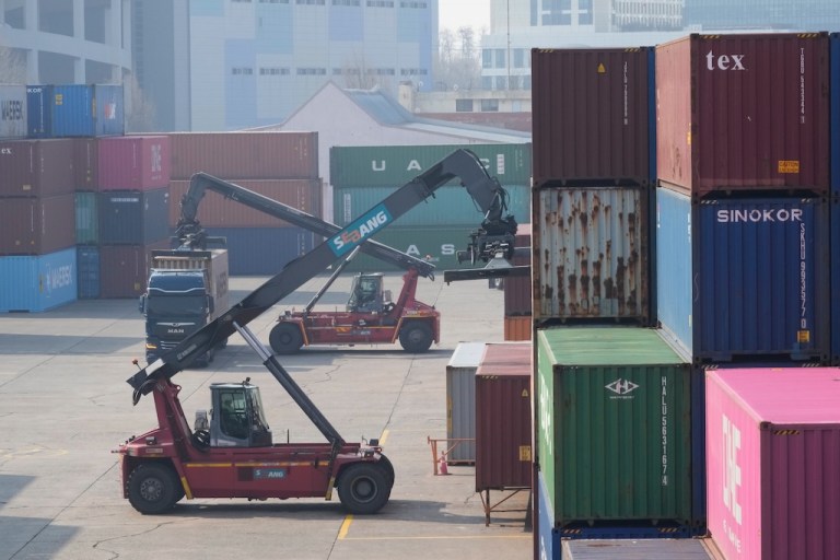 A crane unloads a container from a truck.