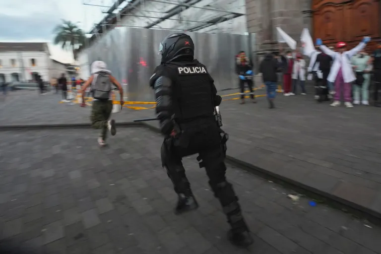 A police officer chases a protester in Ecuador.