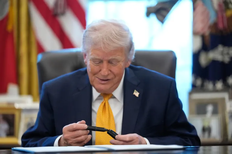 President Donald Trump holds a pen before signing an executive order in the Oval Office