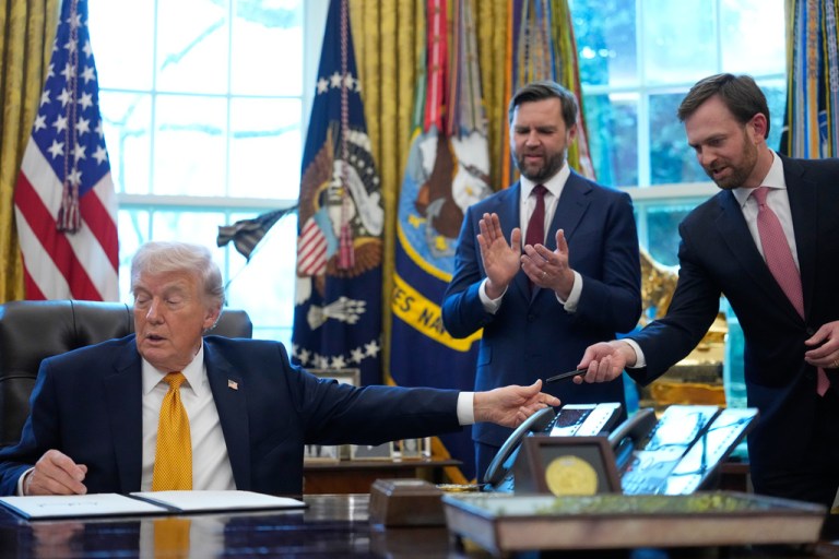 President Donald Trump hands a pen to Federal Trade Commission chairman Andrew Ferguson after he signed an executive order regarding a task force on fraud in the Oval Office of the White House, Monday, March 16, 2026, in Washington, as Vice President JD Vance applauds. (AP Photo/Julia Demaree Nikhinson)