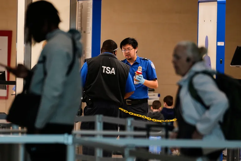 Travelers make their way through a security check point as TSA agents talk at Love Field Airport in Dallas, Monday, March 16, 2026.