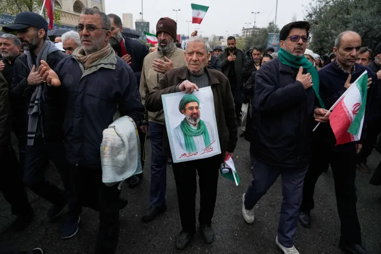People mourn while one of them holds a poster of the Supreme Leader Ayatollah Mojtaba Khamenei.
