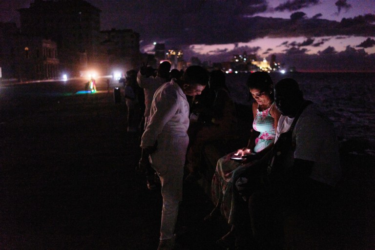 People spend the night in the dark on the Malecon during a blackout in Havana, Cuba, Saturday, March 21, 2026.