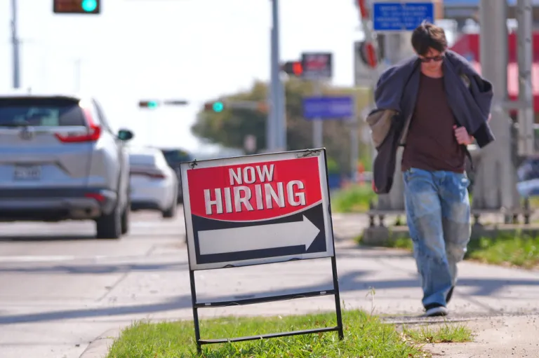 A now hiring sign sits on the side of the road in Garland, Texas.