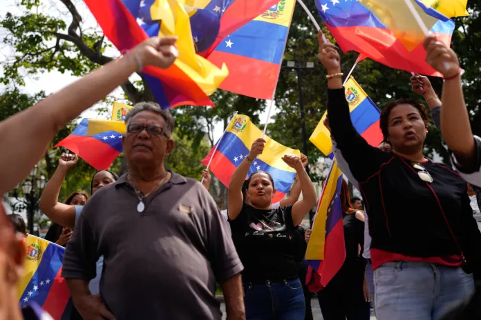 People gather holding Venezuelan flags.
