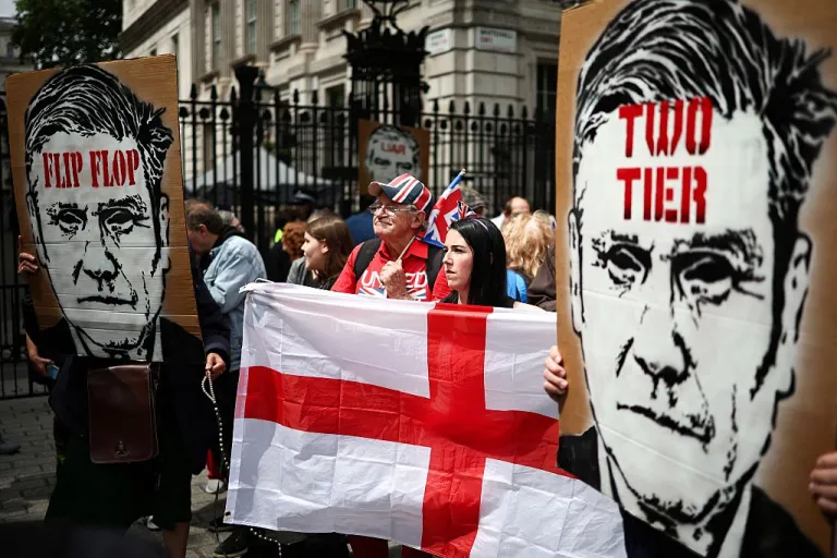 Protestors hold placards depicting Britain's Prime Minister Keir Starmer reading the message 