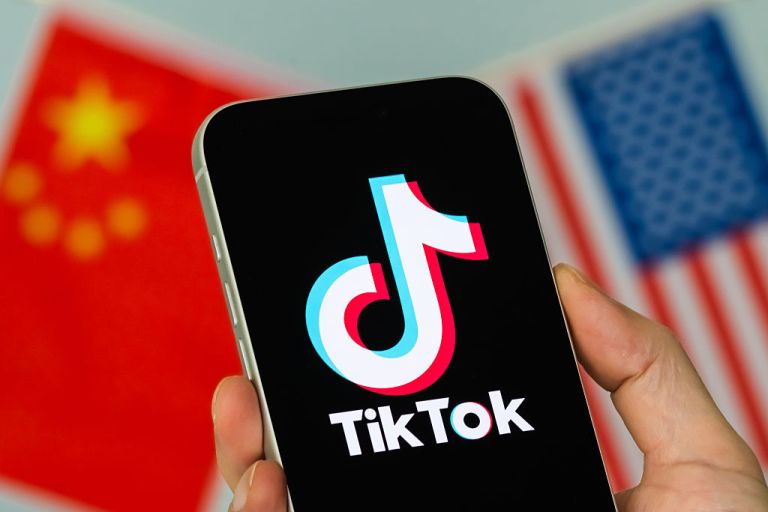 CHONGQING, CHINA - JANUARY 23: In this photo illustration, a person holds a smartphone displaying the TikTok logo, with the Chinese and U.S. flags visible in the background, on January 23, 2026, in Chongqing, China. In a post shared earlier in the day on Truth Social, U.S. President Donald Trump said he helped keep TikTok operating in the United States, citing efforts involving American investors and discussions with Chinese counterparts, and expressed appreciation for Chinese President Xi Jinping's approach toward allowing the deal to proceed amid ongoing U.S. national security scrutiny. (Photo illustration by Cheng Xin/Getty Images)