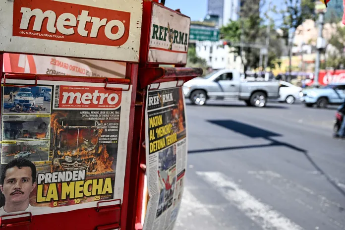 The front page of a local newspaper displays news about the death of Nemesio Oseguera, alias "El Mencho," Mexico's most wanted drug lord in recent years, in Mexico City on February 23, 2026. Mexico has deployed 10,000 troops to quell clashes sparked by the killing of the country's most wanted drug lord, which have left dozens dead, officials said on February 23. Nemesio "El Mencho" Oseguera, leader of the Jalisco New Generation Cartel (CJNG), was wounded on February 22 in a shootout with soldiers in the town of Tapalpa in Jalisco state and died while being flown to Mexico City, the army said. (Photo by Yuri CORTEZ / AFP via Getty Images)